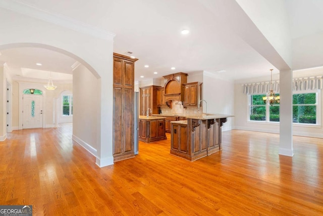 kitchen with a chandelier, a kitchen island, brown cabinetry, a kitchen bar, and pendant lighting