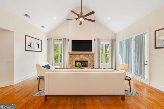 living room featuring plenty of natural light, visible vents, a fireplace, and light wood-style flooring