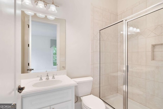 bathroom with toilet, a shower stall, and vanity