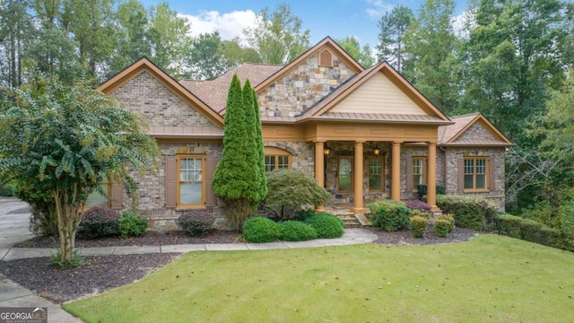 craftsman inspired home with stone siding, a porch, and a front yard