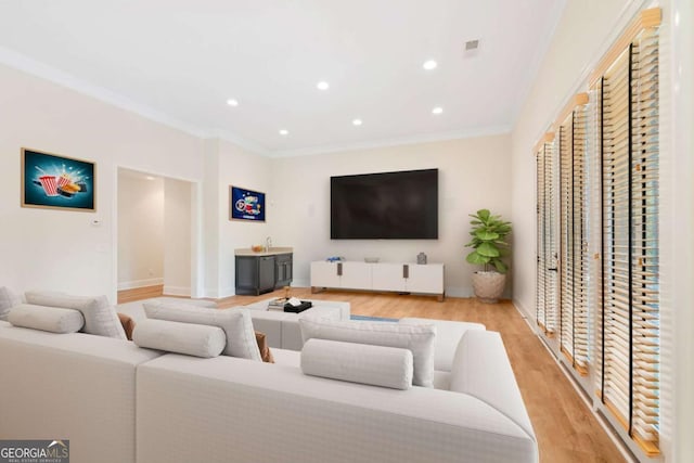 living room featuring recessed lighting, baseboards, crown molding, and light wood finished floors