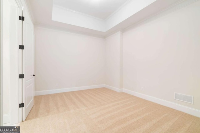 spare room featuring light carpet, ornamental molding, visible vents, and baseboards