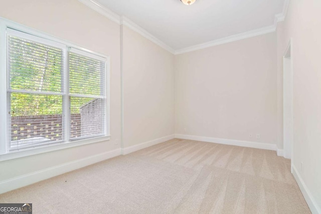 spare room with baseboards, ornamental molding, and light colored carpet