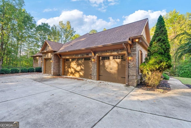 exterior space featuring a shingled roof, brick siding, driveway, and a garage