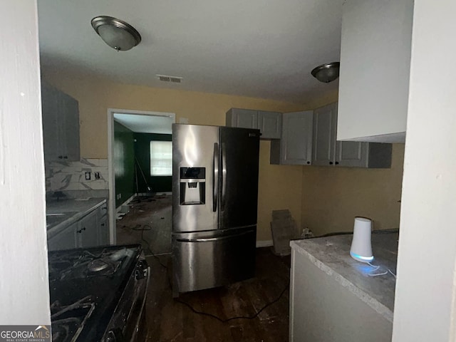 kitchen featuring stainless steel fridge, visible vents, light countertops, gray cabinetry, and gas stove