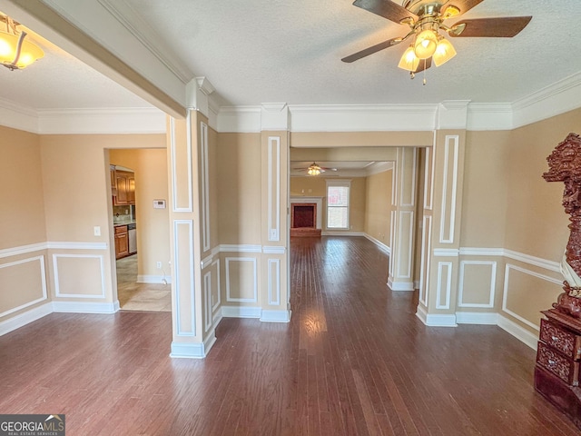 hall with ornate columns, a textured ceiling, dark wood-style floors, and a decorative wall