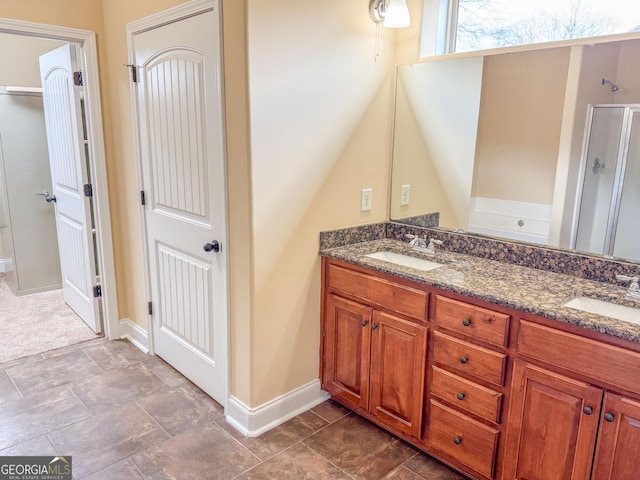 bathroom featuring double vanity, a stall shower, and a sink