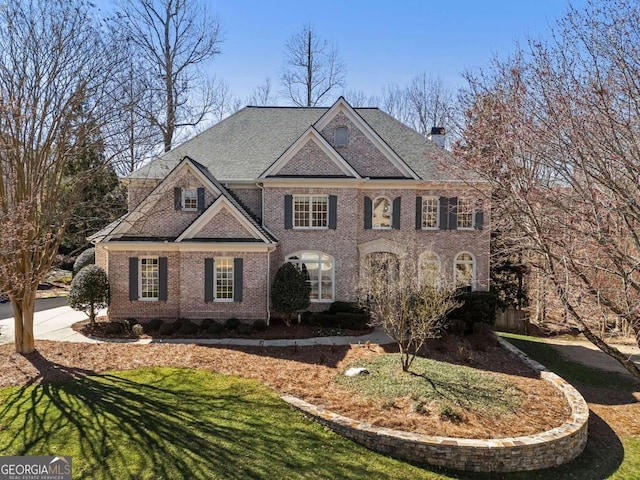 colonial-style house with a front yard, brick siding, and a chimney