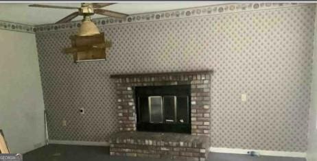 unfurnished living room with a fireplace, baseboards, and wallpapered walls