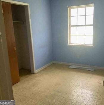 unfurnished bedroom with a closet and baseboards