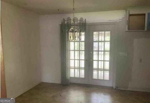 unfurnished dining area featuring a wealth of natural light, french doors, and a notable chandelier