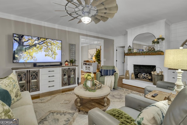 living room with a brick fireplace, crown molding, and wood finished floors