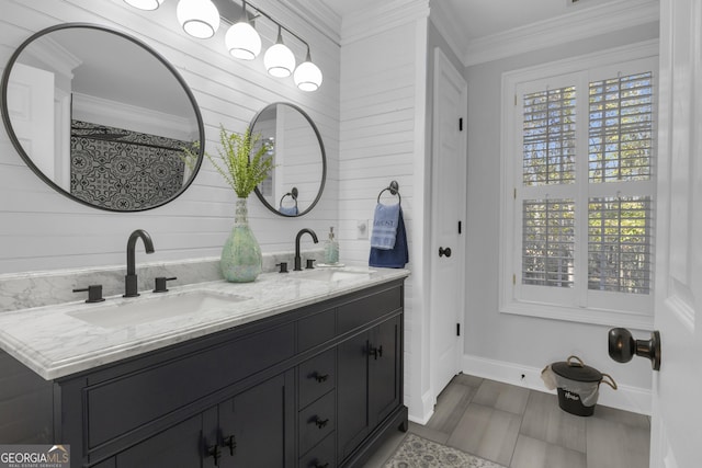 bathroom with crown molding, double vanity, baseboards, and a sink