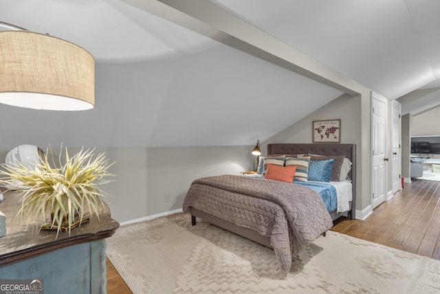 bedroom with vaulted ceiling, baseboards, and wood finished floors