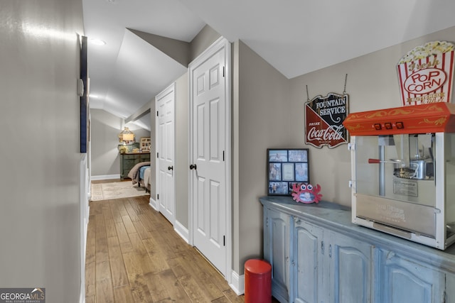 hall featuring vaulted ceiling, baseboards, and wood-type flooring