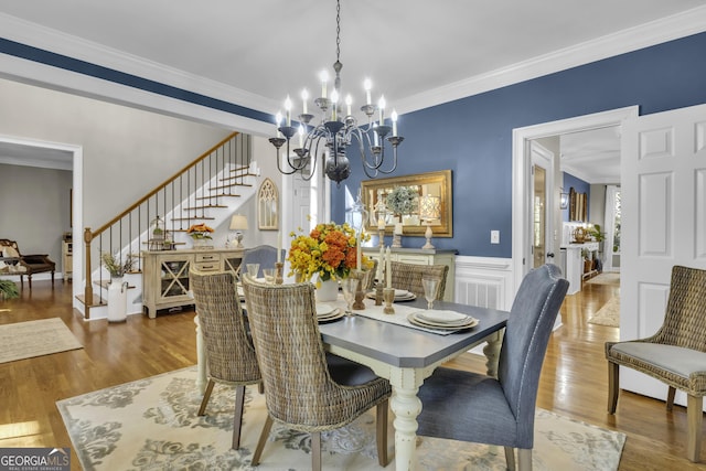 dining space with crown molding, stairway, a wainscoted wall, an inviting chandelier, and wood finished floors