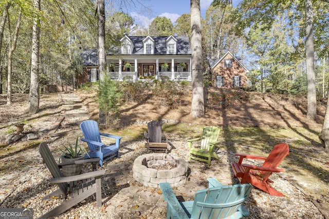 view of yard featuring a porch and an outdoor fire pit