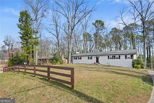 ranch-style home with a front yard and fence