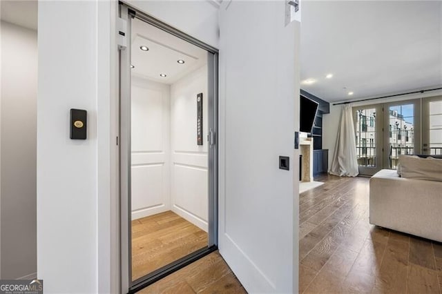 hallway featuring recessed lighting, wood finished floors, and elevator