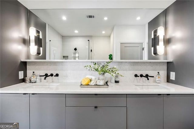 bathroom with visible vents, a sink, tiled shower, and double vanity