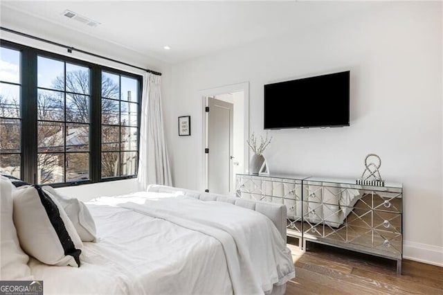 bedroom featuring baseboards, visible vents, wood finished floors, and recessed lighting