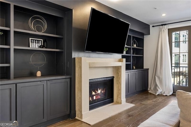 living room with plenty of natural light, wood finished floors, and a glass covered fireplace