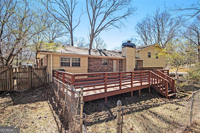 rear view of property featuring brick siding, a chimney, a gate, fence, and a deck