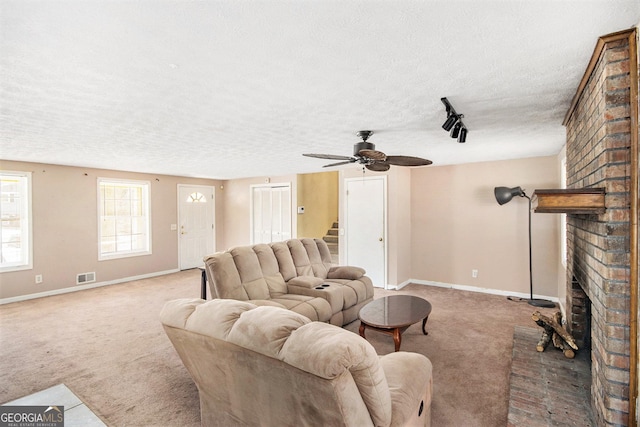 carpeted living room featuring baseboards, visible vents, stairway, a textured ceiling, and a fireplace