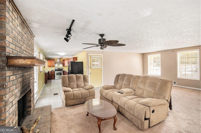 living room featuring rail lighting, a brick fireplace, light carpet, and a textured ceiling