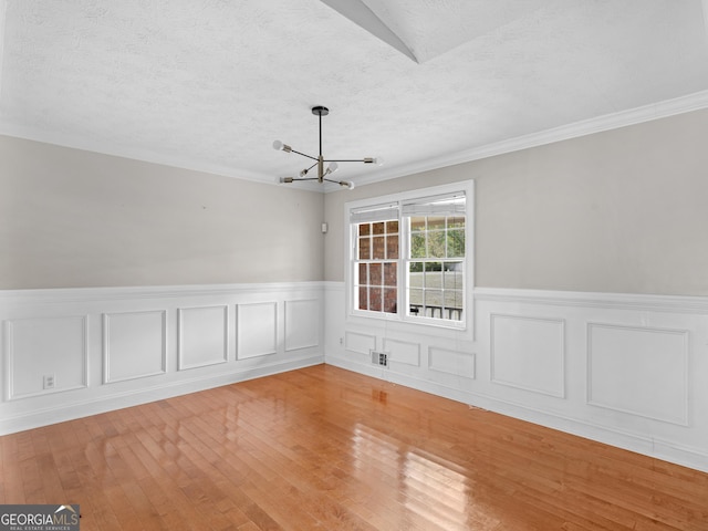 spare room featuring a textured ceiling, crown molding, a chandelier, and light wood-style floors