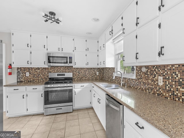 kitchen featuring light stone counters, stainless steel appliances, backsplash, white cabinets, and a sink