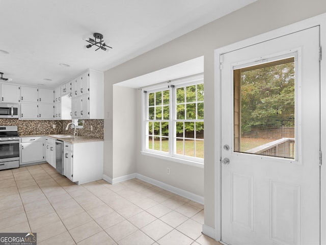 kitchen featuring stainless steel appliances, tasteful backsplash, light countertops, white cabinets, and a sink