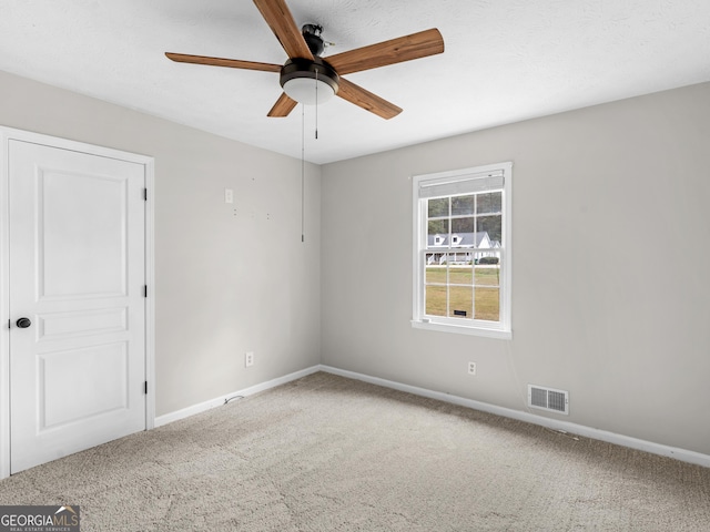 spare room with a ceiling fan, carpet flooring, visible vents, and baseboards