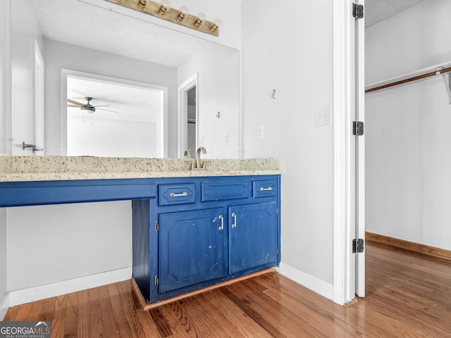 bathroom with ceiling fan, wood finished floors, vanity, and baseboards