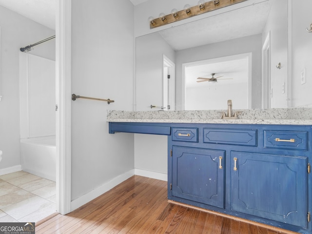 bathroom with ceiling fan,  shower combination, wood finished floors, and baseboards