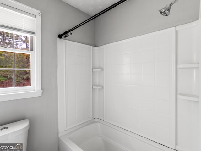 bathroom with a wealth of natural light, tub / shower combination, a textured ceiling, and toilet