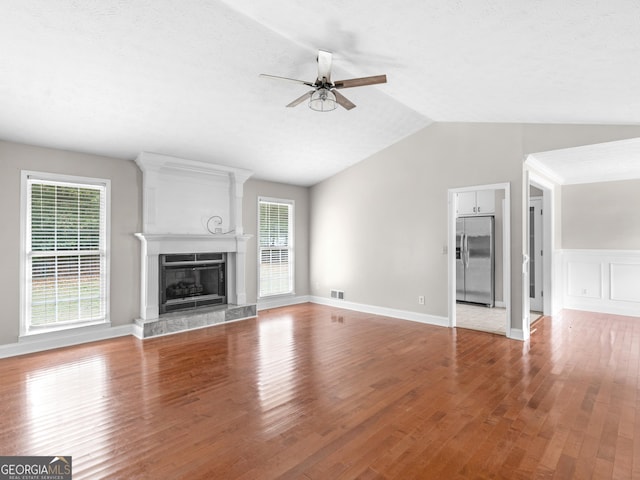 unfurnished living room featuring light wood-style flooring, plenty of natural light, a high end fireplace, and a ceiling fan