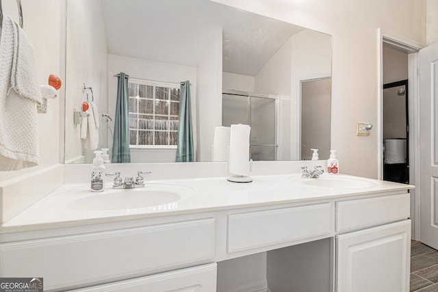 bathroom featuring double vanity, a shower stall, and a sink