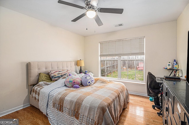 bedroom with baseboards, visible vents, ceiling fan, and light wood finished floors
