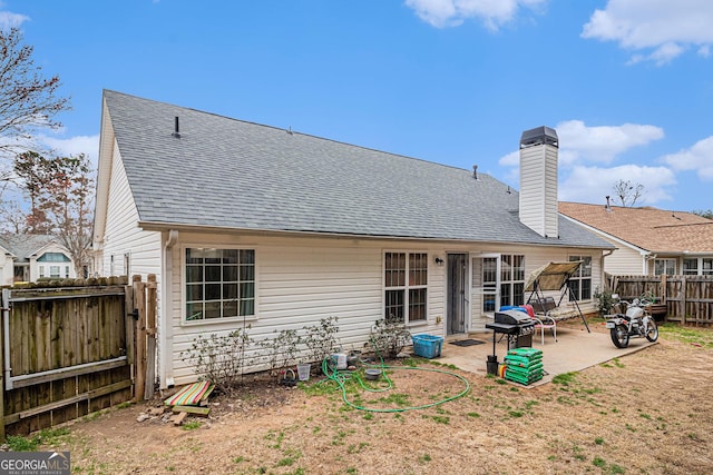 rear view of property with a patio area, a fenced backyard, a chimney, and roof with shingles