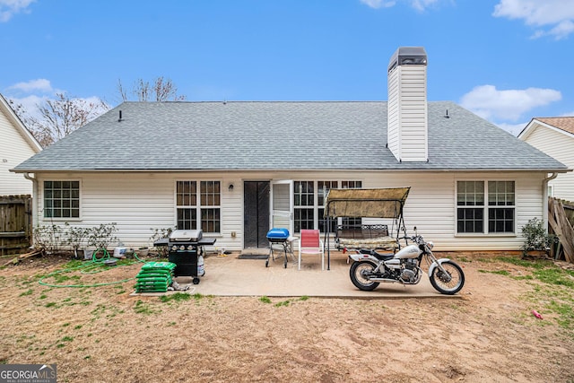 back of property with a chimney, roof with shingles, a patio area, and fence