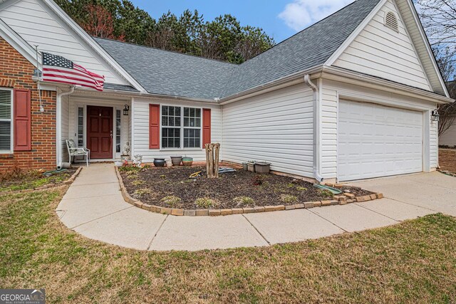 view of front of house featuring a garage, concrete driveway, and a shingled roof