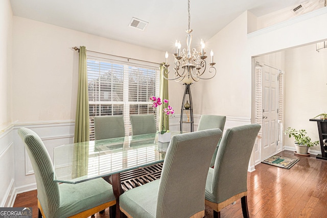 dining space with hardwood / wood-style flooring, visible vents, vaulted ceiling, and a chandelier