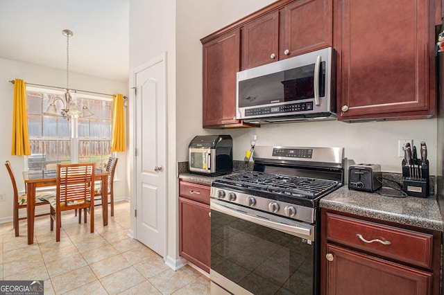 kitchen featuring light tile patterned floors, dark countertops, appliances with stainless steel finishes, hanging light fixtures, and a chandelier