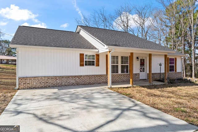 ranch-style house featuring covered porch, concrete driveway, a shingled roof, and brick siding