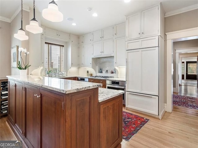 kitchen with light wood-style flooring, ornamental molding, stainless steel appliances, and light stone counters