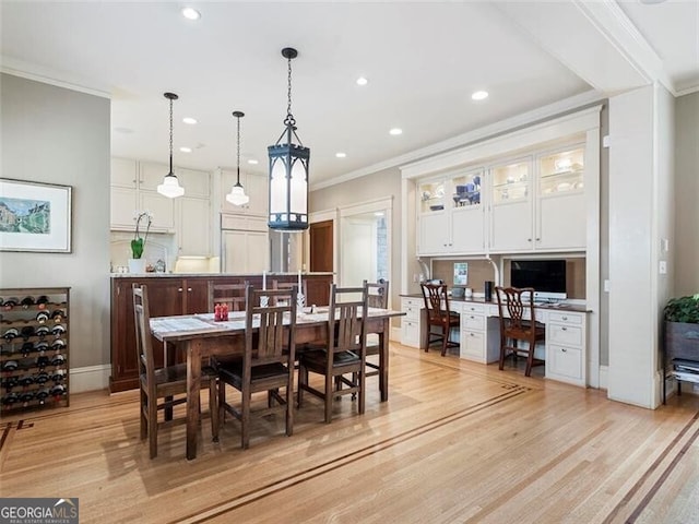 dining space with light wood finished floors, baseboards, ornamental molding, built in desk, and recessed lighting