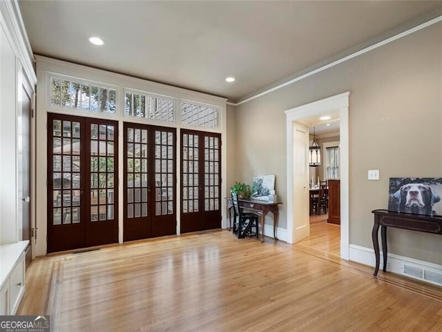 entryway featuring ornamental molding, light wood-type flooring, and french doors