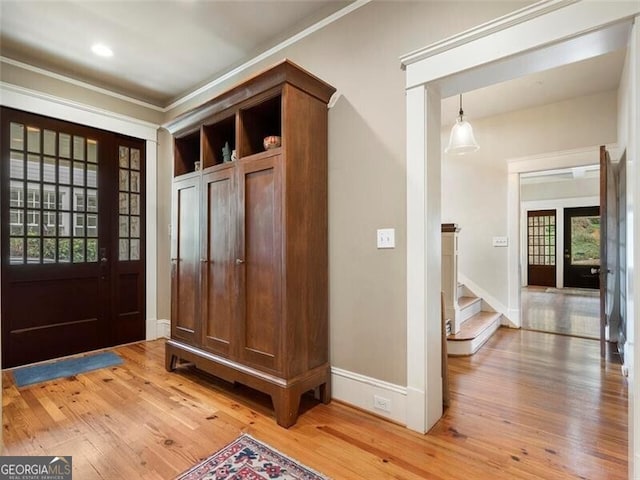 mudroom with baseboards, french doors, ornamental molding, and light wood-style floors