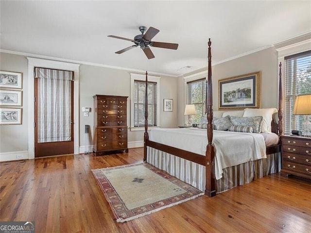 bedroom featuring multiple windows, crown molding, baseboards, and hardwood / wood-style flooring